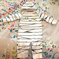 a white and black striped cat onesie laying on a floral bed sheet with yellow eyes