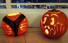 two carved pumpkins sitting next to each other on a tile floor with city lights in the background