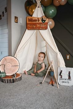 a baby sitting in front of a teepee tent