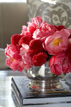 a vase filled with pink flowers sitting on top of a table next to a book