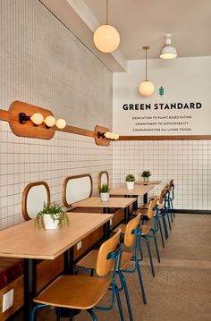 the interior of a restaurant with tables and chairs lined up against the wall, along with potted plants