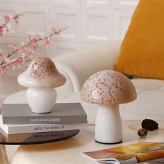 two white mushrooms sitting on top of each other next to books and a vase with pink flowers