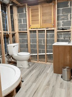 a bathroom that is being remodeled with wood flooring and exposed walls in the background