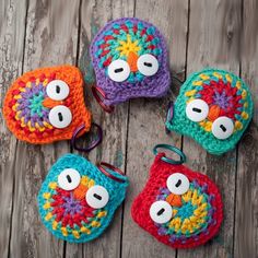 four crocheted owl coin purses sitting on top of a wooden table