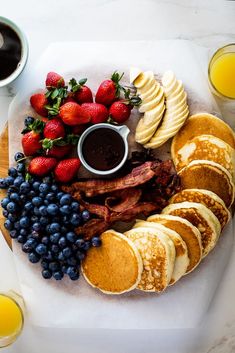 pancakes, bacon, and fruit are arranged on a plate