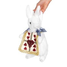 a white stuffed rabbit wearing a dress with gold sequins on it's chest