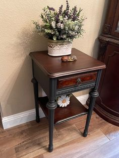 a potted plant sitting on top of a wooden table next to a shelf with flowers