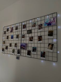 a white wall with many pictures on it and some lights around the perimeter, along with several magnets