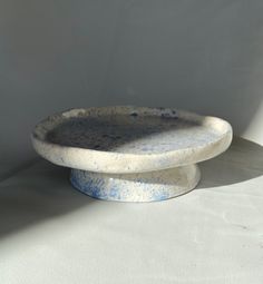 a blue and white bowl sitting on top of a table next to a white wall