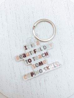 a keychain with words on it sitting on top of a white table next to a pair of scissors