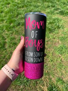 a person holding up a pink and black cup with the words mom of boss on it