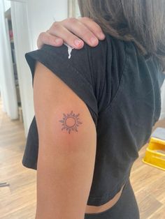 a woman with a small sun tattoo on her arm