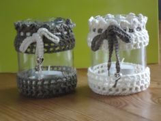 two glass jars with candles in them sitting on a table