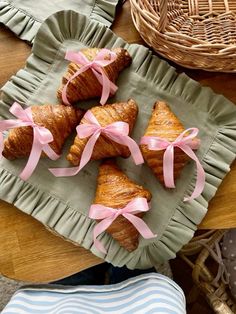 croissants with pink bows are sitting on a plate next to other pastries