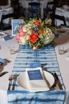 the table is set with blue and white napkins, silverware, and flowers