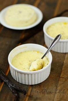 two small white bowls filled with food on top of a wooden table next to a spoon