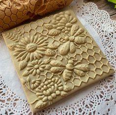 an intricately carved piece of art on a doily next to some flowers and leaves