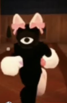 a black cat with pink ears and big eyes is dancing in front of an audience