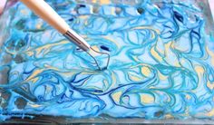 a blue and yellow swirled cake sitting on top of a pan covered in icing