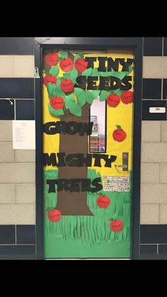 an apple tree made out of paper and cut outs on the door to a classroom