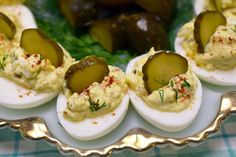 deviled eggs topped with pickles on a platter