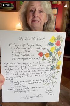 an older woman holding up a sign with flowers on it