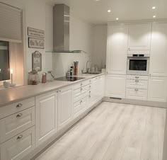 a kitchen with white cabinets and counter tops, along with an oven on the wall