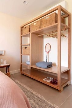 a bed room with a neatly made bed and a wooden shelving unit in it