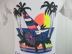 "Vintage 1980s vacation travel t shirt. Made of white cotton. has multi color graphics with sun, surf, palm trees and sailboat. Reads: Diamond Hotel and Resorts Playacar. Size medium. Actual measurements are: 35\" around the chest 35\" around the waist 18\" shoulder seam to shoulder seam 26.5\" overall length In very good condition with small spot on the back(photo)." Retro Multicolor T-shirt For Vacation, White Tropical Print T-shirt For Vacation, Multicolor Hawaiian Graphic Print T-shirt, White Hawaiian T-shirt With Sublimation Print, White Surfing T-shirt For Vacation, Vintage White T-shirt For Surfing, White T-shirt With Tropical Print For Vacation, White T-shirt With Tropical Print For Beach, Tropical Multicolor Graphic Print T-shirt