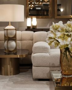 a living room with couches, tables and flowers in vases on the coffee table