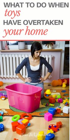 a woman sitting on the floor in front of a pink tub with toys all around her