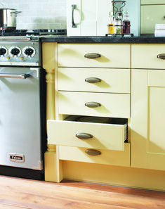 a kitchen with yellow cabinets and black counter tops