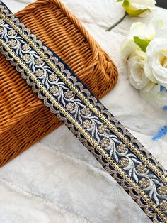 a close up of a ribbon on a table with flowers and a basket in the background