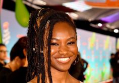 a smiling woman with dreadlocks on her head in front of a group of people