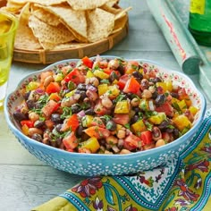 a bowl filled with beans and vegetables next to tortilla chips