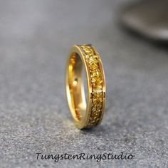 a gold wedding ring with yellow diamonds on the inside and outside, sitting on a gray surface