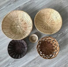 four woven baskets sitting on top of a wooden floor