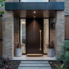 the entrance to a modern home with two large planters on either side of the door