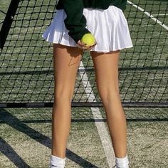 a woman holding a tennis ball and racquet on top of a tennis court