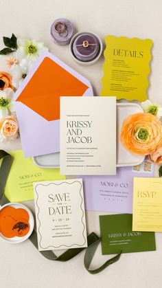 the wedding stationery is laid out on top of each other, including an orange and yellow envelope