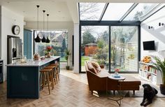 a living room filled with furniture next to a kitchen and dining room table in front of a large window