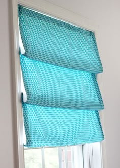 a window with blue roman shades in a room