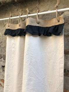 two white towels hanging on a clothes line next to a brick wall and stone building