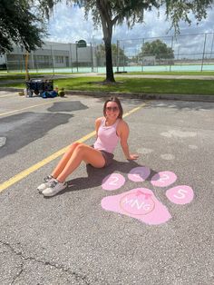 a woman is sitting on the ground with her paw prints painted in pink and white