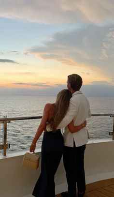 a man and woman standing on the deck of a cruise ship looking out at the ocean