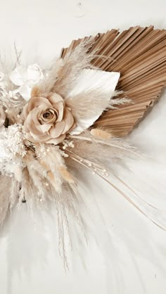 an arrangement of feathers and flowers on a white surface