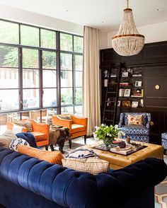 a living room with blue couches, orange chairs and a chandelier hanging from the ceiling