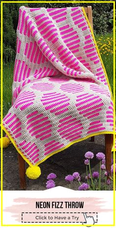 a pink and white blanket sitting on top of a wooden chair next to purple flowers