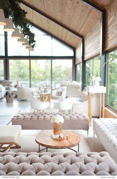 a living room filled with lots of furniture next to large glass windows on the wall