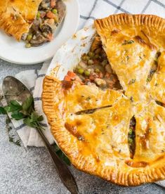 a pie sitting on top of a white plate next to a fork and bowl filled with food